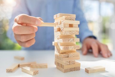 Planlama, risk ve stratejide iş adamı kumar kulesine tahta blok koyuyor.