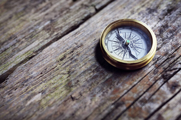Antique golden compass on wood background concept for direction, travel, guidance or assistance