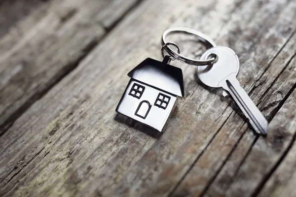 不動産 住宅や賃貸物件のための木製の床板の概念に休んで家の形のキーチェーン上の家の鍵 — ストック写真