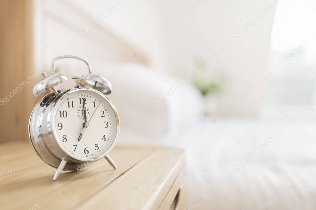 Alarm clock morning wake-up time on bedside table with copy space