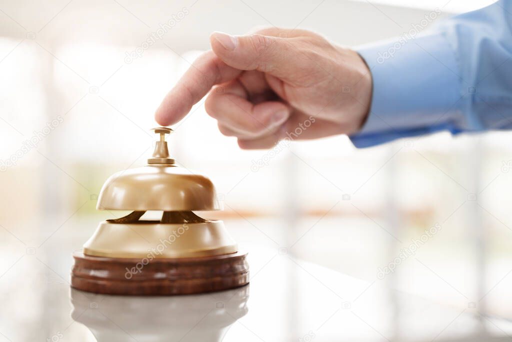 Businessman ringing a hotel reception service bell to attract attention