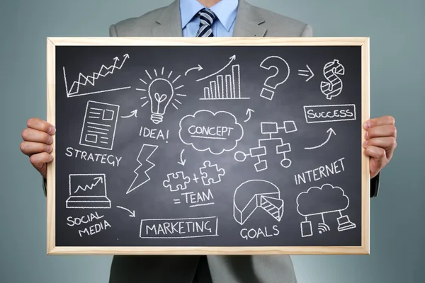 Businessman holding a blackboard with brainstorming chalk drawing — Stock Photo, Image