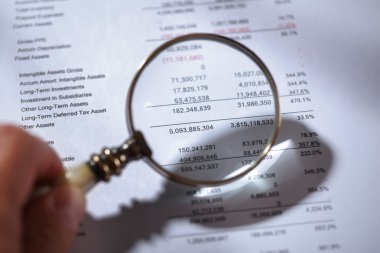 Magnifying glass on financial report clipart