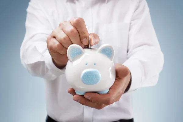 Empresário inserindo uma moeda em um banco porquinho — Fotografia de Stock