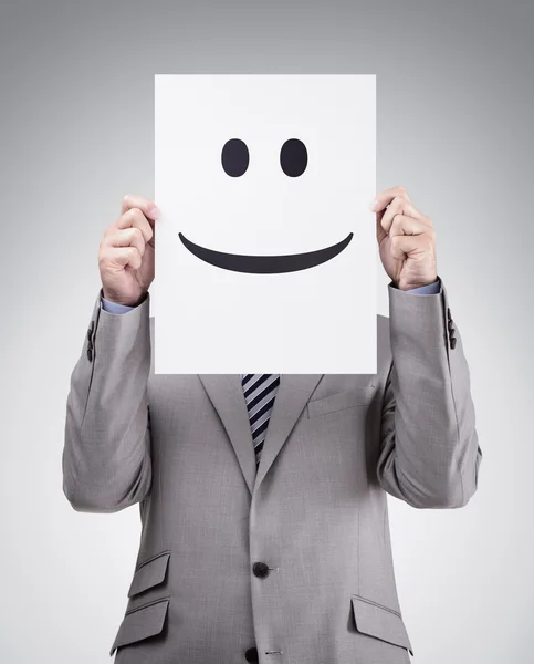 Businessman holding card with smiley face Stock Picture