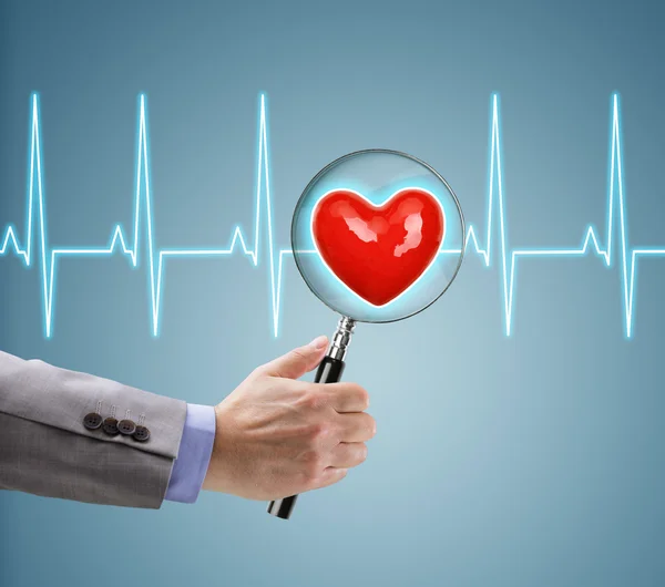 Doctor with magnifying glass on heart — Stock Photo, Image