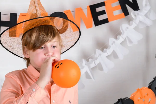 Ein Blonder Junge Mit Orangefarbenem Hut Bläst Einen Orangefarbenen Luftballon — Stockfoto