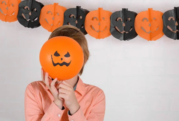 Ein Junge Versteckt Sein Gesicht Hinter Einem Orangefarbenen Halloween Luftballon — Stockfoto