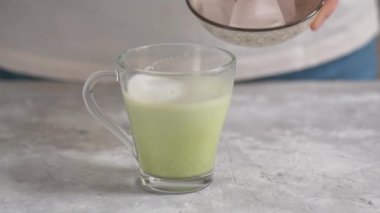 Kadın elleri, cam bardaktaki karışık kibrit çayına sıcak süt ekliyor. Matcha yapmak, sağlıklı ve doğal bir içecek.