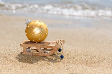 Okyanus yakınlarındaki tropikal sahilde altın top ile Noel kızağı, bir yaz Noel ve kış bayramı konsepti, seçici odaklanma. Mutlu Noeller ve mutlu yıllar.