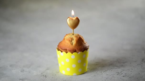 4K自家製バレンタインデーカップケーキまたはマフィングレーの背景に黄色の形のハート型のキャンドル お祝いバレンタインの日 結婚式のカップルの記念日 誕生日 流行の色 食用の贈り物 ズームイン — ストック動画