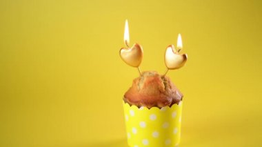 4k Sevgililer Günü keki ya da sarı arka planda sarı süslemeli iki altın kalpli muma sahip kek, Sevgililer Günü Kutlaması. Tatil, evli çiftin yıldönümü, doğum günü, tek göz.