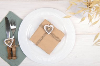 Romantik masa, tahta kalp süslemesi ve kuru bitki içeren kraft kağıdı hediye ediyor. Sevgililer Günü, Doğum Günü ya da Anneler Günü için hazırlanmış çevre dostu sıfır atık hediyesi.