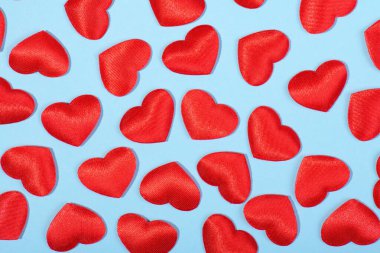 Pastel mavi arka planda, kumaşın kırmızı kalplerinden oluşan desen Sevgililer Günü arka planında, kapat.