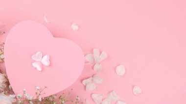 Pembe kalp şeklinde hediye paketi pembe arka planda küçük çiçekli, Sevgililer Günü, bayram, evli çiftin yıldönümü, doğum günü geçmişi.