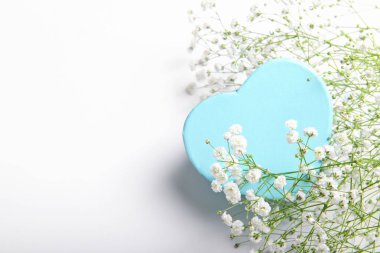 Mavi kalp şeklinde hediye kutusu beyaz arka planda küçük çiçekli, Sevgililer Günü, bayram, evli çiftin yıldönümü, doğum günü geçmişi.