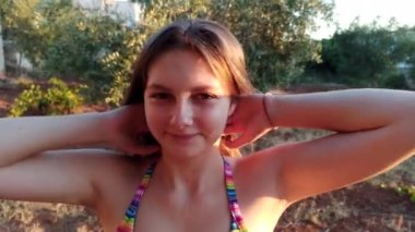 Gün batımında gülümseyen bir kızın yüzüne yakın güzel gözlerle, saçlarına, portresine dokunarak, yaz güneşinin altında dinlenerek