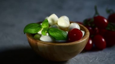 4K taze apulian mozzarella peynirini taze fesleğen yaprağıyla ahşap bir kasede kapat ve yakınlaştır.