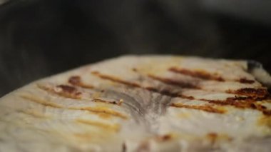 Kılıçbalığı Xiphais gladius bifteği. Izgara tavada pişiyor. Duman ve buharla.