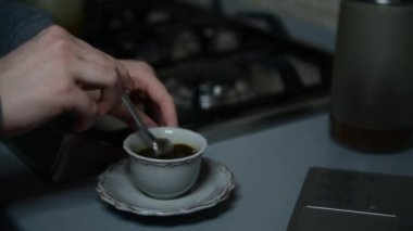 Bir kız mutfakta İtalyan moka ile kahve espresso hazırlar, iyi bir sabah kahvesi rutini uyanın, 13. adım, bir fincan şekeri karıştıran kadın elleri, yakın çekim, seçici odaklanma.