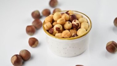 Bir kasede soyulmuş fındık ve beyaz ahşap bir arka planda bütün fındık, yakınlaştır.