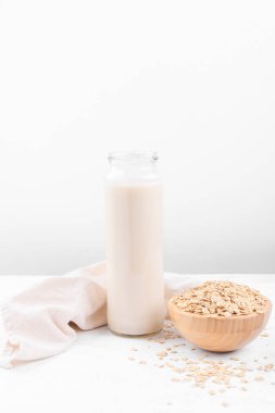 Şişede yulaf sütü ve beyaz masada yulaf lapası.
