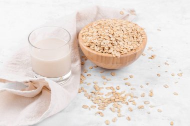 Yulaf sütlü bardak ve beyaz taş masada yulaf ezmeli bir kase.