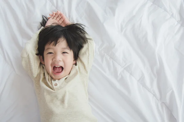 Азиатский ребенок лежит на белой кровати — стоковое фото