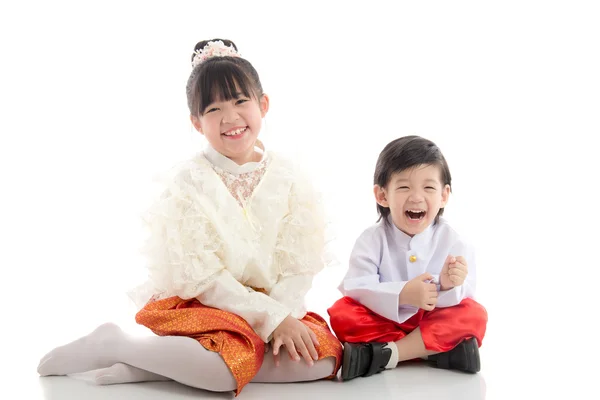 Счастливые дети в тайском традиционном костюме сидят на белом фоне — стоковое фото