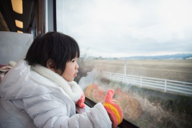 Tren pencere dışında bakarak mutlu Asyalı çocuk