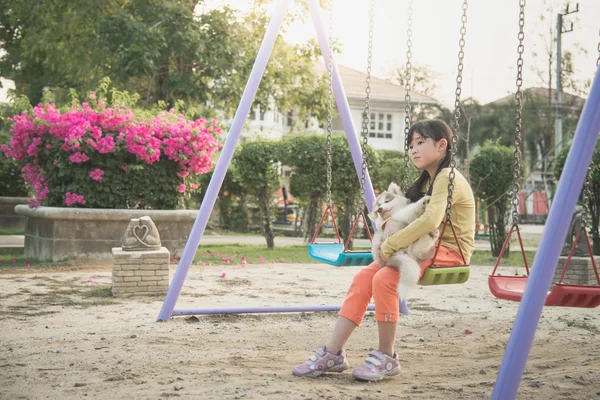 Ásia menina e siberiano husky filhote sentado no corrente swing — Fotografia de Stock