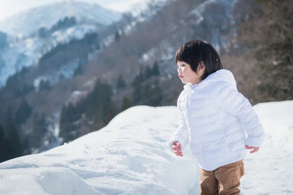 Asian boy in winter clothes with snow background — Stock Photo, Image