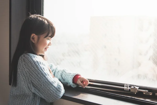 Девушка смотрит в окно — стоковое фото