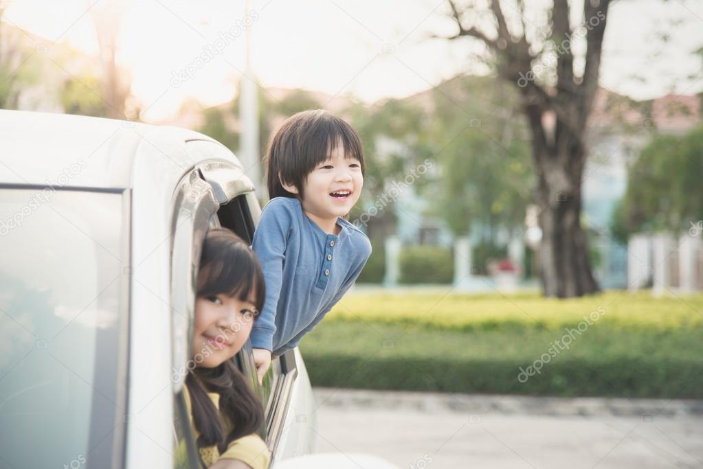 Happy asian children sitting in the car