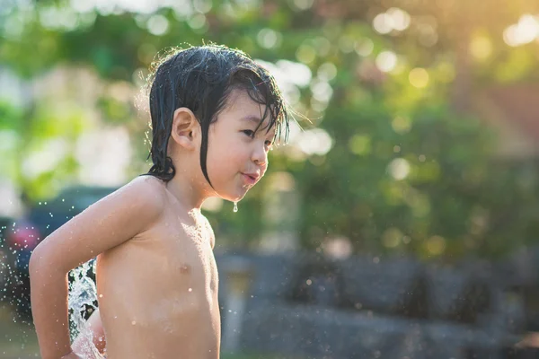 Lindo asiático chico tiene divertido jugando en agua de un manguera al aire libre — Foto de Stock