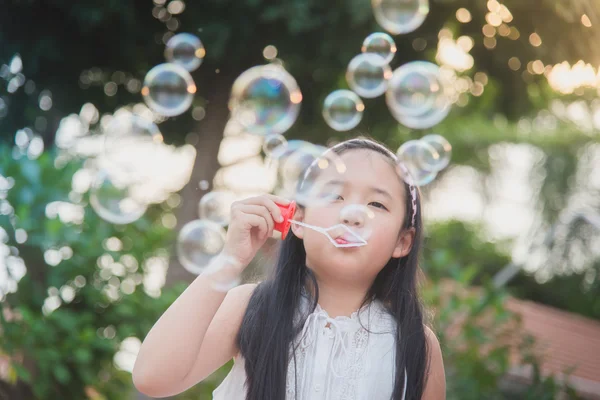 Милая азиатка надувает мыльный пузырь. — стоковое фото