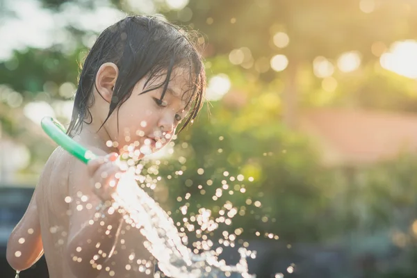 Niedlich asiatische junge hat Spaß spielen in Wasser aus ein Schlauch im Freien — Stockfoto