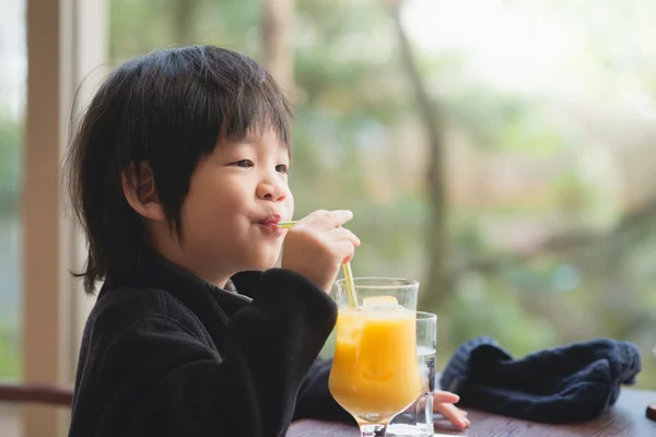 Ребенок пьет свежий апельсиновый сок — стоковое фото