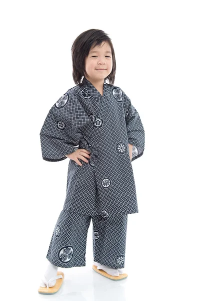 Счастливый азиатский мальчик в кимоно стоит на белом фоне — стоковое фото