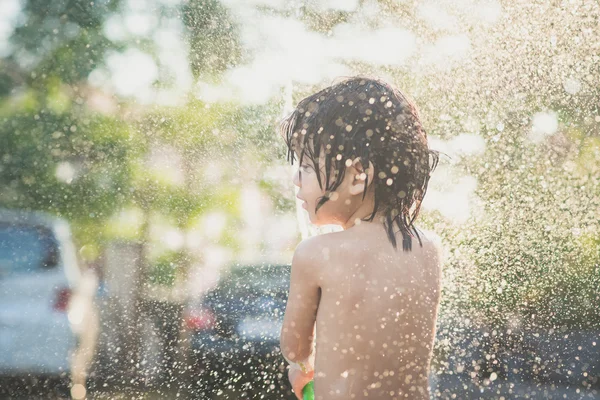 Lindo asiático chico tiene divertido jugando en agua de un manguera — Foto de Stock