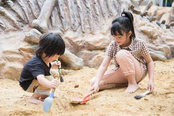 Små asiatiska barn har roligt gräva i sanden — Stockfoto