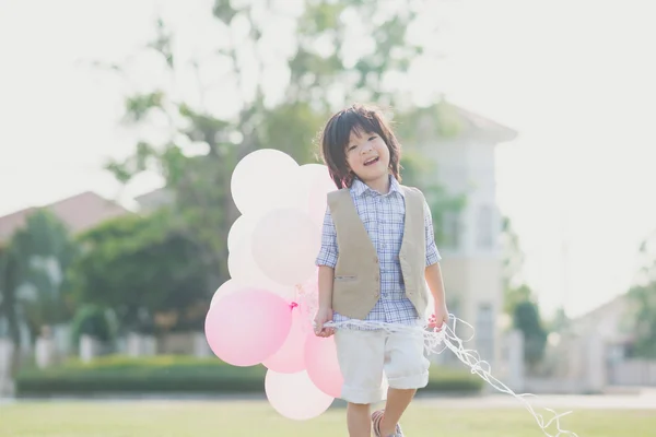 Söta asiatiska barn med många ballonger spelar i parken under su — Stockfoto