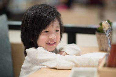 Asyalı çocuk bir kaşık ve çatal ile tutarak