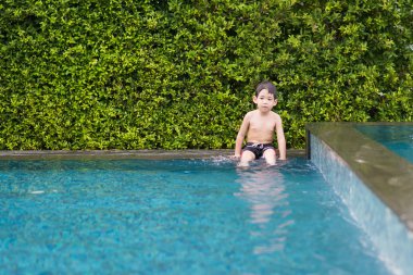Asyalı çocuk yüzme havuzunda oynayan