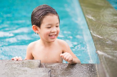 Asyalı çocuk yüzme havuzunda oynayan
