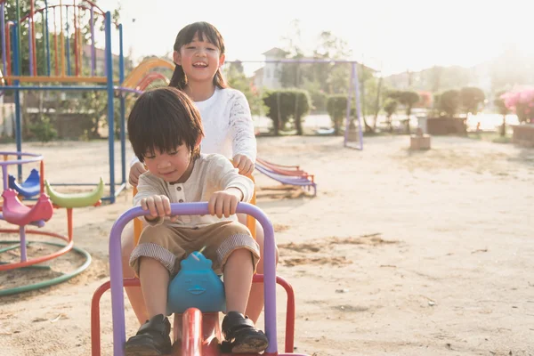 Söta asiatiska barn ridning gungbräda styrelsen på lekplatsen — Stockfoto