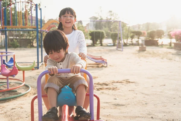 Lindo asiático niño equitación balancín en el parque infantil — Foto de Stock