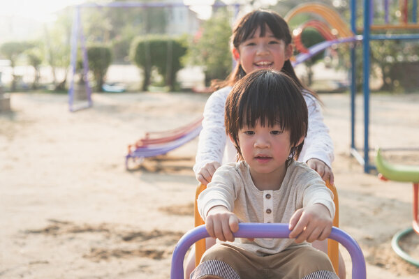 Милый азиатский ребенок катается на качелях на детской площадке
 