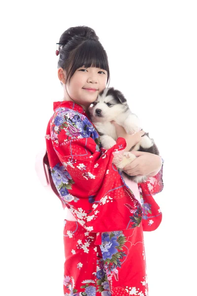 Poco asiático chica en rojo kimono jugando con un siberiano husky pu — Foto de Stock