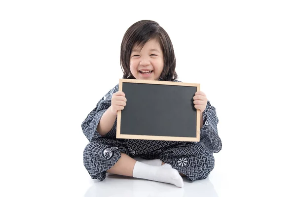 Niedlich asiatische junge in Kimono holding schwarz board — Stockfoto